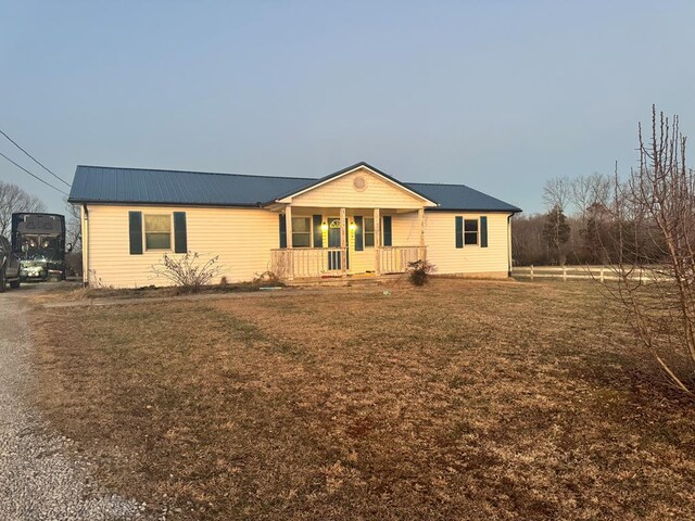 ranch-style house featuring covered porch, metal roof, and a front yard