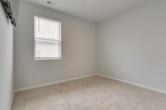 empty room featuring visible vents, light carpet, and baseboards