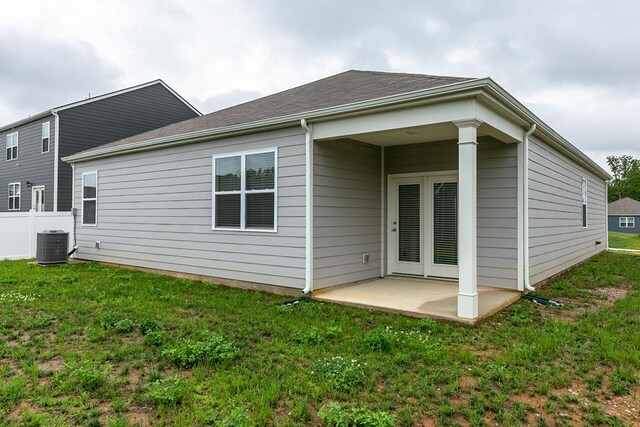 back of property featuring a patio, a yard, central AC, and a shingled roof