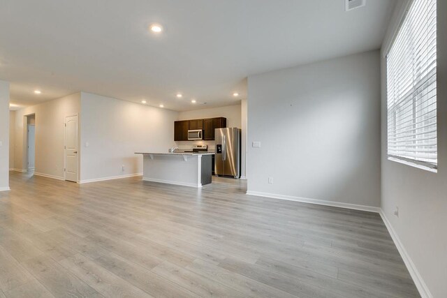 unfurnished living room featuring baseboards, light wood-type flooring, and recessed lighting