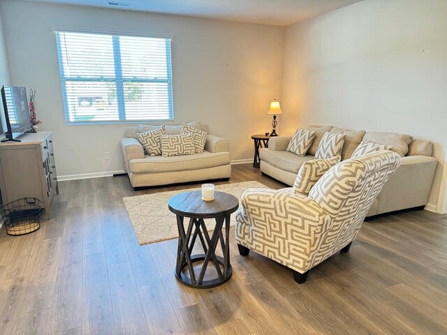 living room with wood finished floors, visible vents, and baseboards