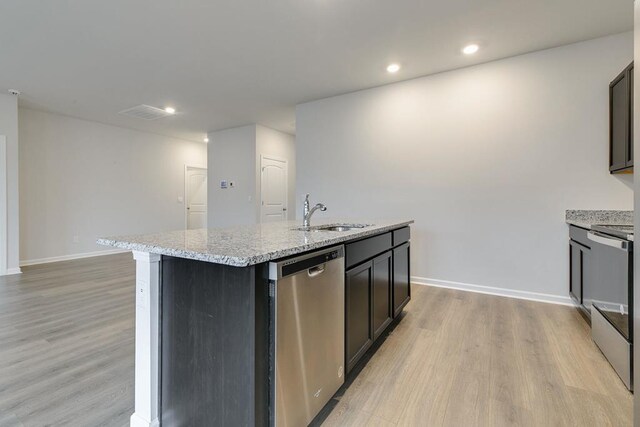 kitchen featuring a sink, light wood-style floors, range, dishwasher, and a center island with sink