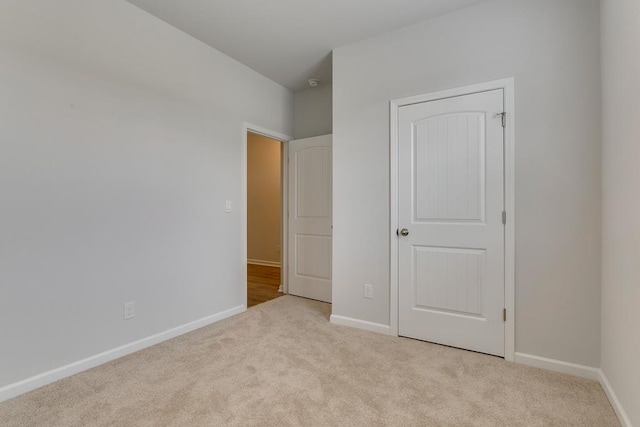 unfurnished bedroom with baseboards and light colored carpet