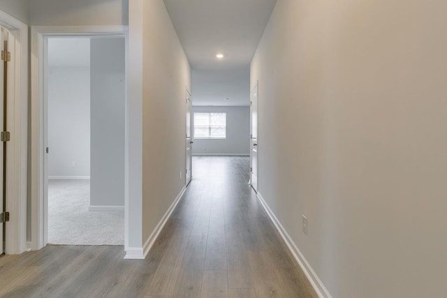 hall with light wood-style flooring and baseboards