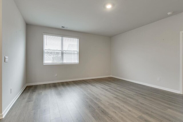 spare room with visible vents, baseboards, and wood finished floors