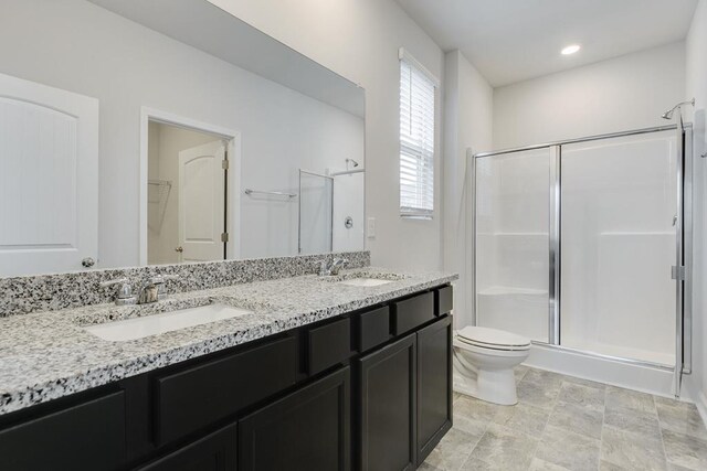 bathroom featuring a spacious closet, a sink, toilet, and a shower stall