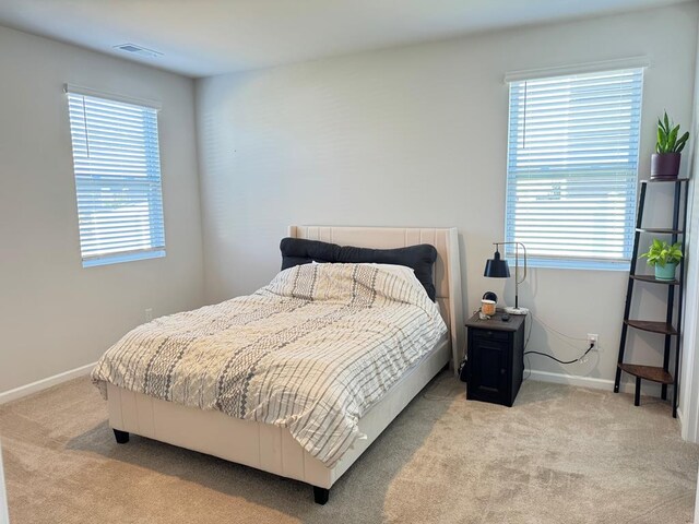 bedroom featuring light colored carpet, visible vents, and baseboards