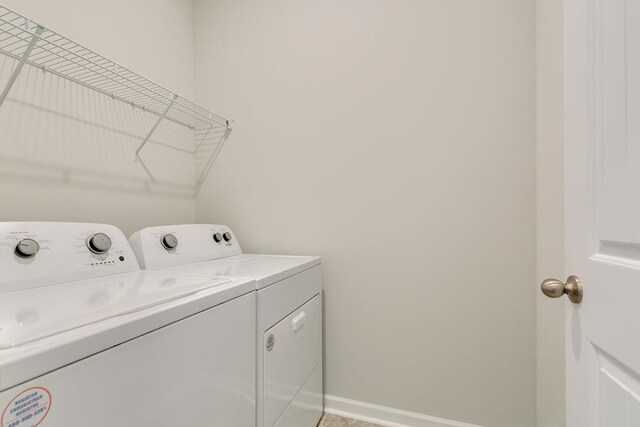 clothes washing area with washing machine and dryer, laundry area, and baseboards