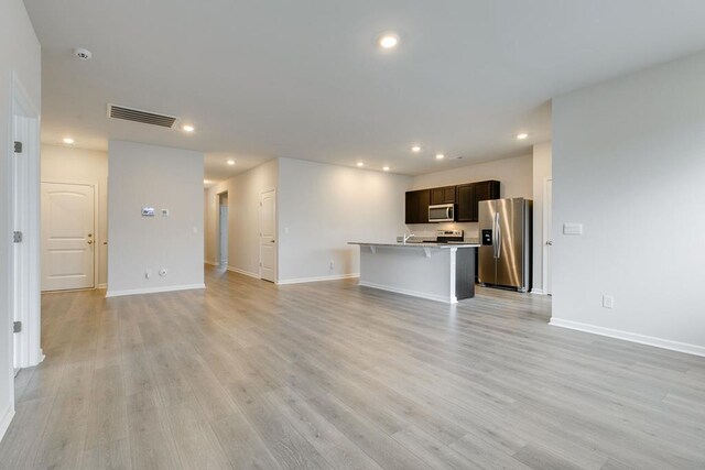 unfurnished living room featuring light wood-type flooring, baseboards, visible vents, and recessed lighting