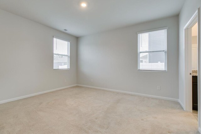 spare room featuring light carpet, baseboards, and visible vents