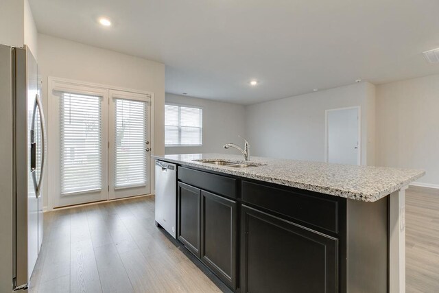 kitchen with recessed lighting, appliances with stainless steel finishes, a sink, an island with sink, and light wood-type flooring