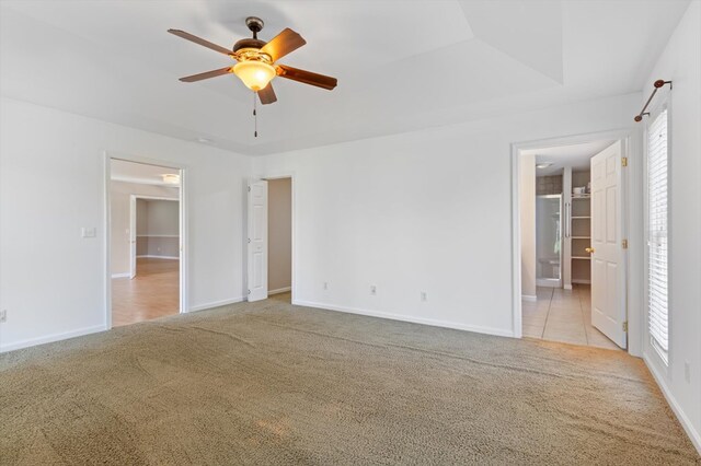 unfurnished bedroom featuring light carpet, multiple windows, and a tray ceiling