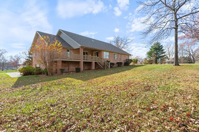 rear view of property featuring stairs, a yard, and brick siding