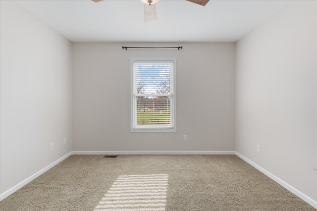 spare room with light colored carpet, visible vents, and baseboards