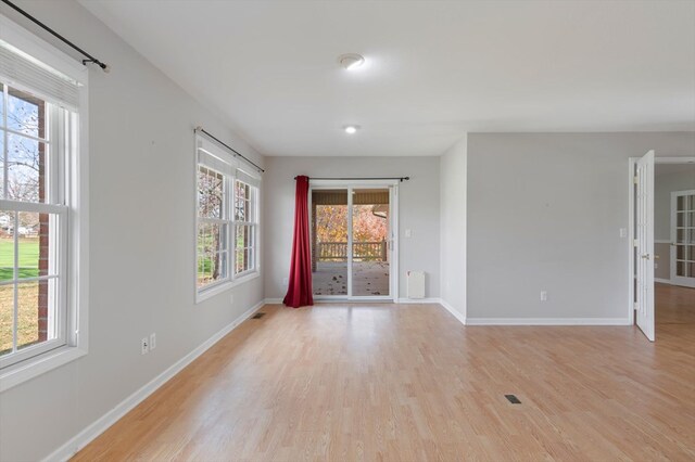 spare room featuring light wood-type flooring, visible vents, and baseboards