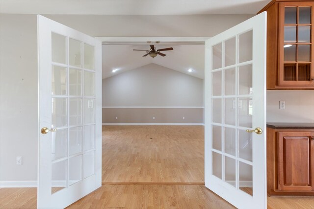 unfurnished room featuring baseboards, a ceiling fan, vaulted ceiling, french doors, and light wood-type flooring