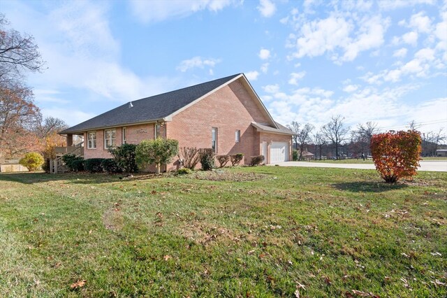 view of property exterior with brick siding, a yard, driveway, and an attached garage