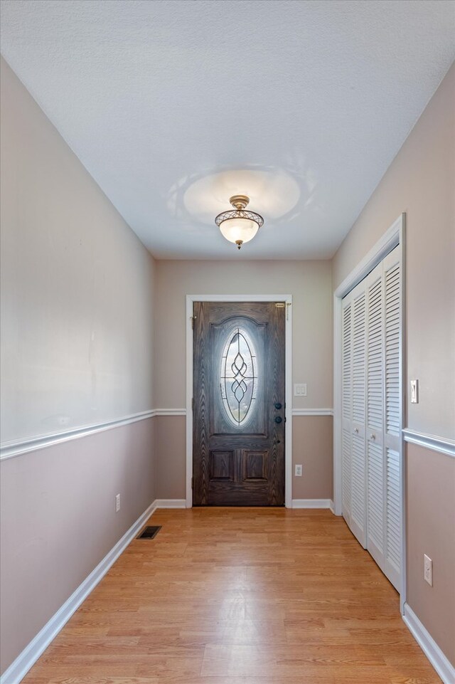 entrance foyer featuring light wood-style floors, visible vents, and baseboards