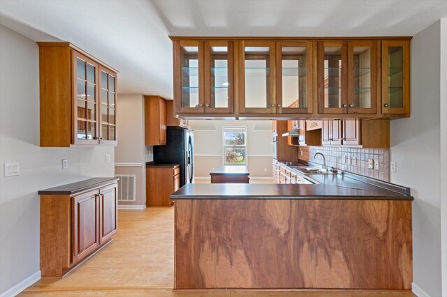 kitchen with glass insert cabinets, dark countertops, and a peninsula