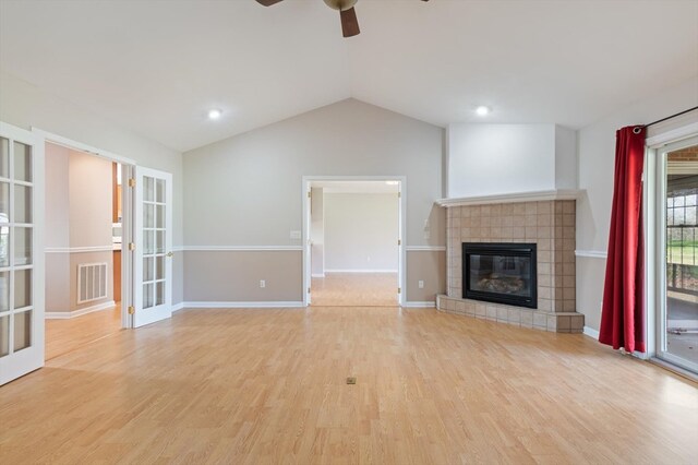 unfurnished living room featuring french doors, lofted ceiling, visible vents, light wood-type flooring, and a tile fireplace