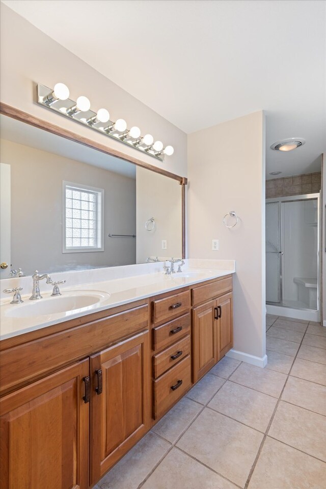 bathroom featuring double vanity, tile patterned flooring, a sink, and a shower stall