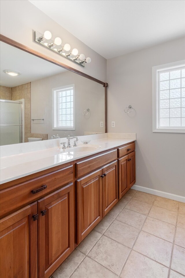 full bath featuring a stall shower, tile patterned flooring, vanity, and baseboards