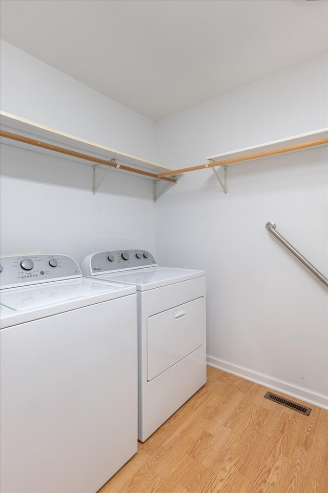 laundry area featuring visible vents, separate washer and dryer, light wood-type flooring, laundry area, and baseboards