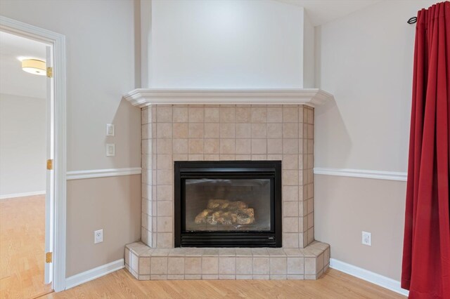 interior details featuring baseboards, wood finished floors, and a glass covered fireplace