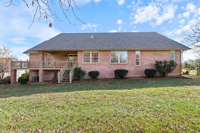 rear view of property with a yard, brick siding, stairway, and central air condition unit