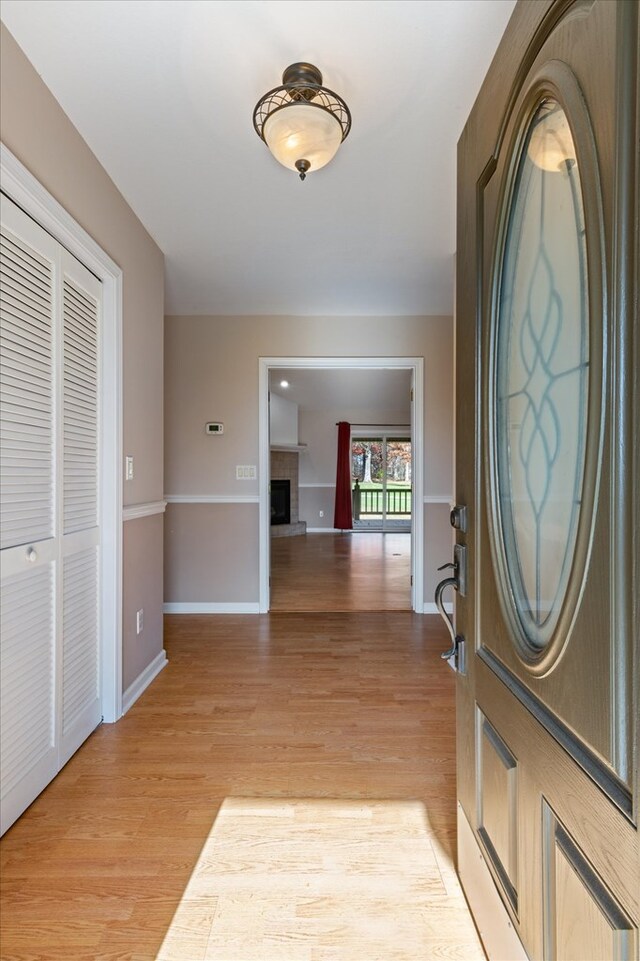 entrance foyer featuring light wood-style floors, a fireplace, and baseboards