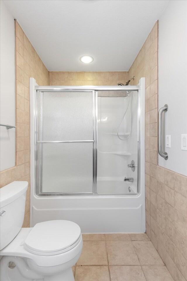 full bath with enclosed tub / shower combo, tile walls, toilet, and tile patterned floors