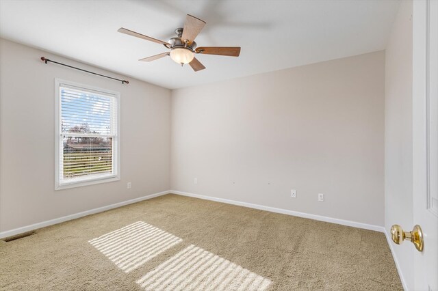 spare room featuring baseboards, visible vents, a ceiling fan, and light colored carpet