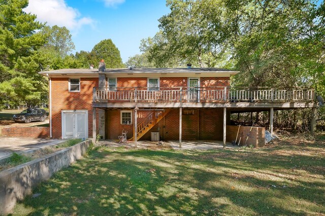 rear view of house with stairway, brick siding, a yard, and a deck