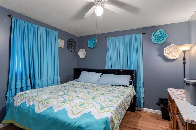 bedroom featuring a textured ceiling, wood finished floors, a ceiling fan, and baseboards