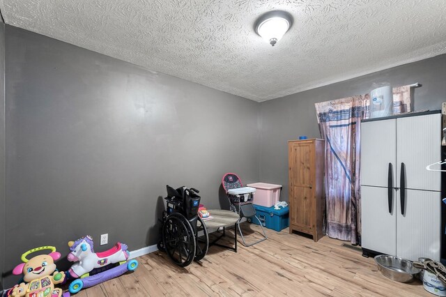 interior space with baseboards, a textured ceiling, and light wood finished floors