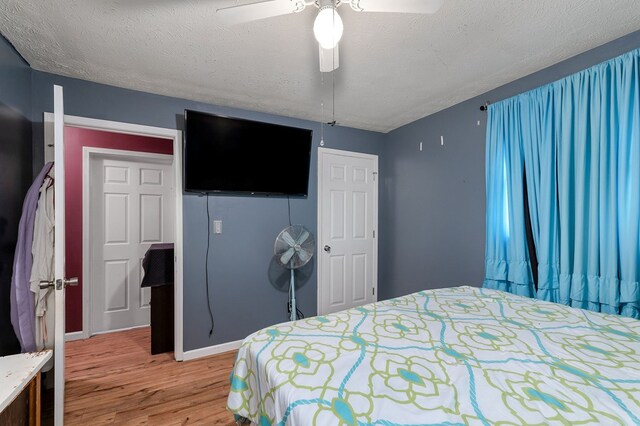 bedroom featuring baseboards, ceiling fan, light wood-style flooring, and a textured ceiling