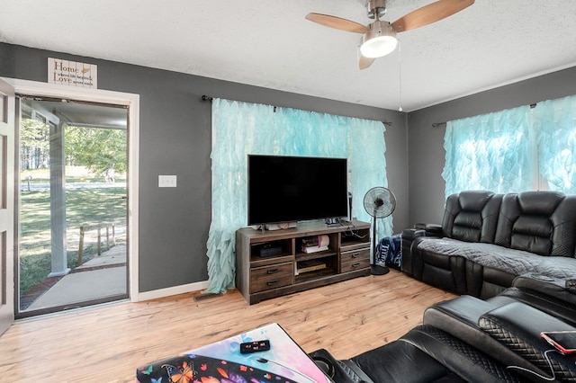 living area with a textured ceiling, ceiling fan, wood finished floors, and baseboards