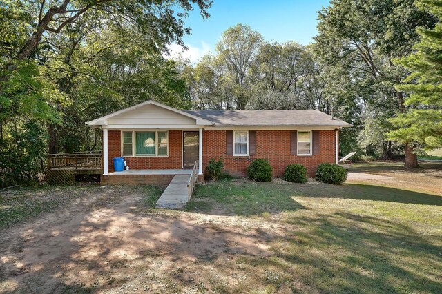 view of front facade with a porch, brick siding, and a front lawn