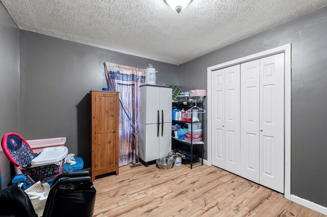 bedroom with light wood-style flooring, a closet, and a textured ceiling