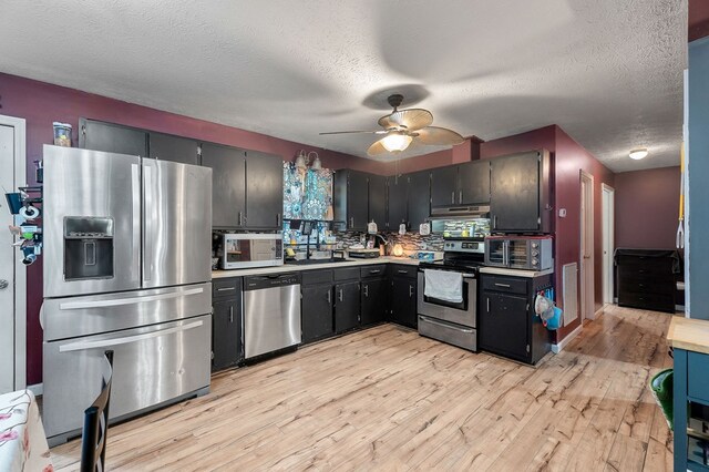 kitchen featuring a textured ceiling, ceiling fan, light countertops, appliances with stainless steel finishes, and light wood finished floors