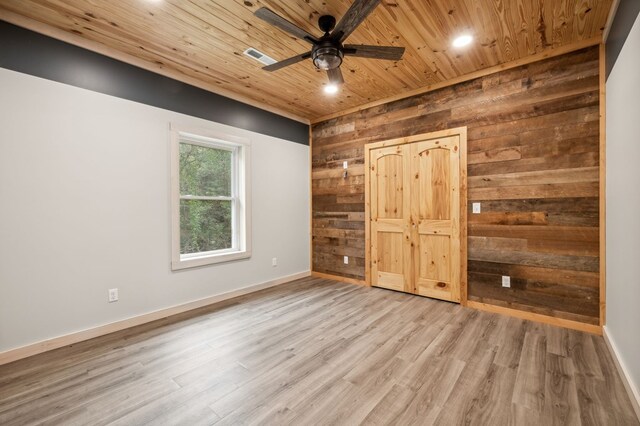 unfurnished bedroom with wooden ceiling, wooden walls, baseboards, and wood finished floors