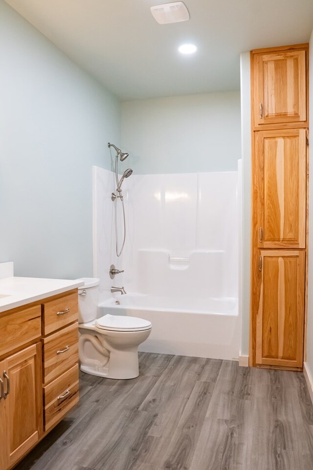 full bathroom featuring washtub / shower combination, vanity, toilet, and wood finished floors