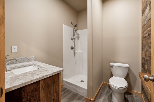 full bathroom with baseboards, toilet, wood finished floors, vanity, and a shower stall