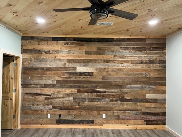 interior details with wooden ceiling, wooden walls, wood finished floors, visible vents, and a ceiling fan