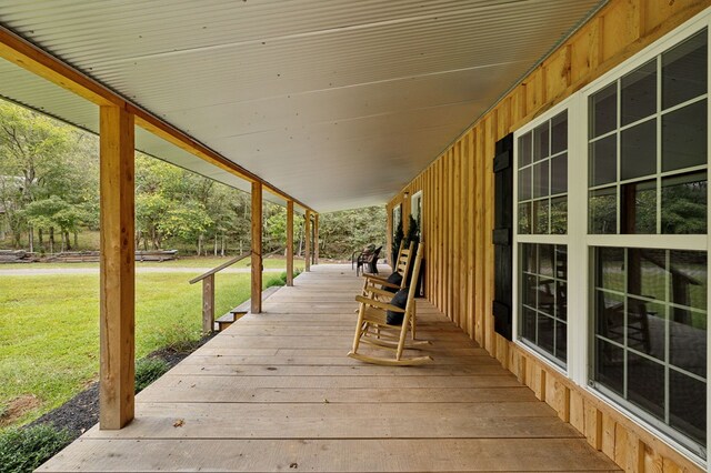 wooden terrace featuring covered porch and a lawn