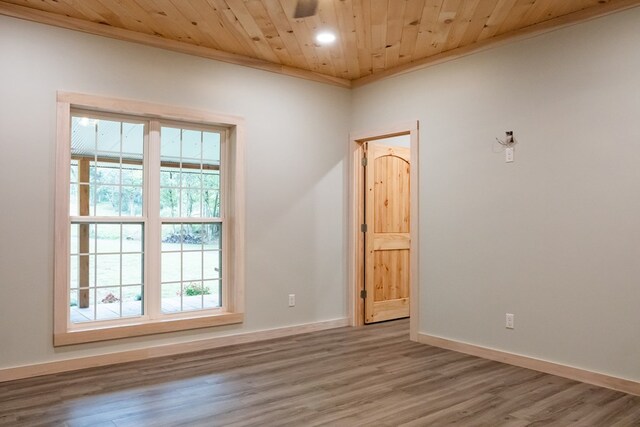 empty room with crown molding, wooden ceiling, wood finished floors, and baseboards