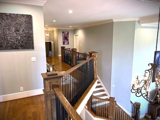 corridor featuring baseboards, wood finished floors, crown molding, an upstairs landing, and recessed lighting