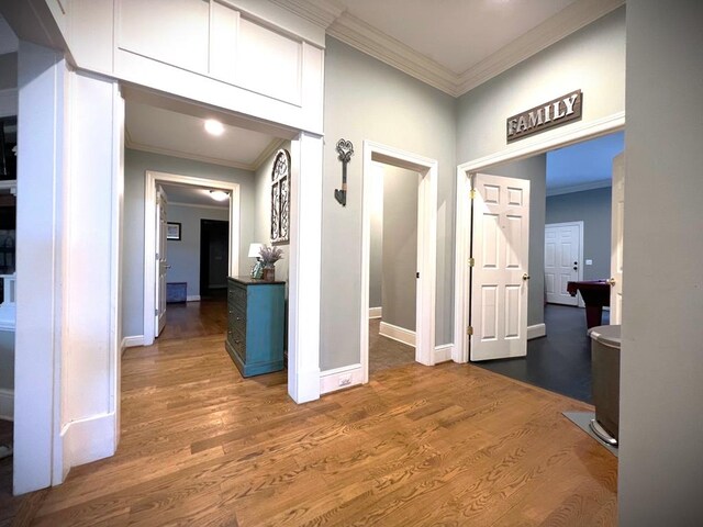 corridor featuring dark wood-style floors, baseboards, and ornamental molding