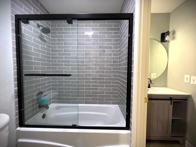 full bath with toilet, bath / shower combo with glass door, and vanity