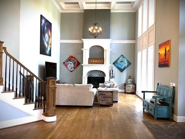 living area with a large fireplace, a high ceiling, coffered ceiling, and an inviting chandelier